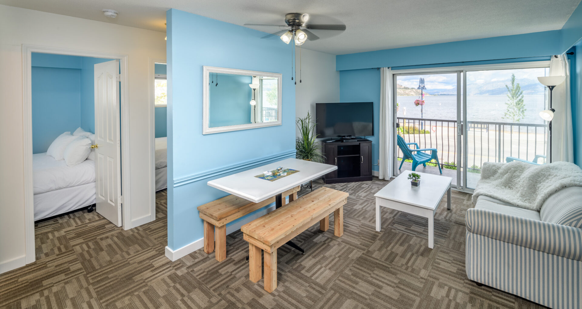 okanagan lakefront resort suite living room with blue walls and a dining table with wooden benches