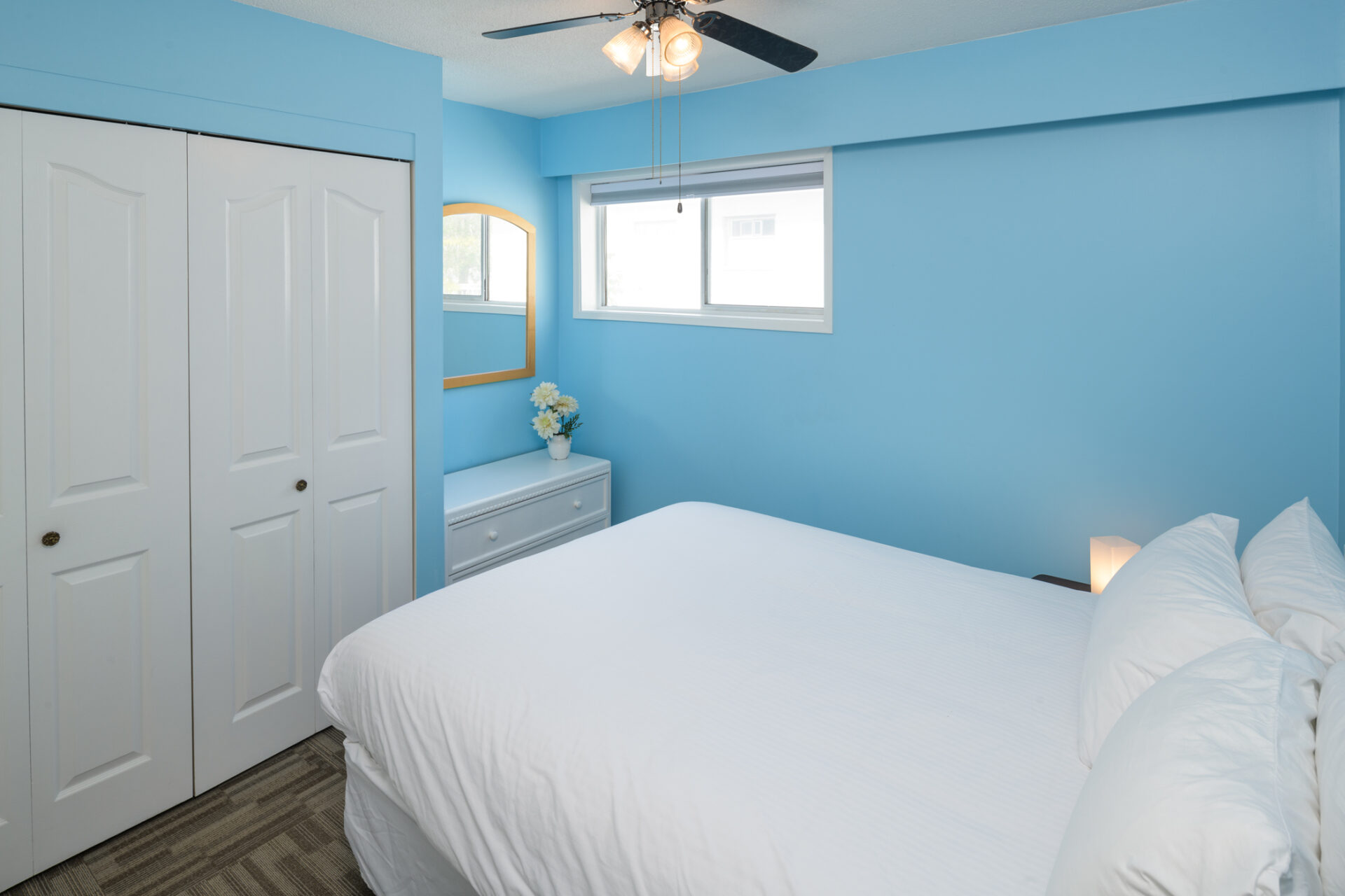 okanagan lakefront resort private bedroom with blue walls, white linens and a white dresser