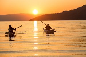 couple kayaking on lake with sunset behind