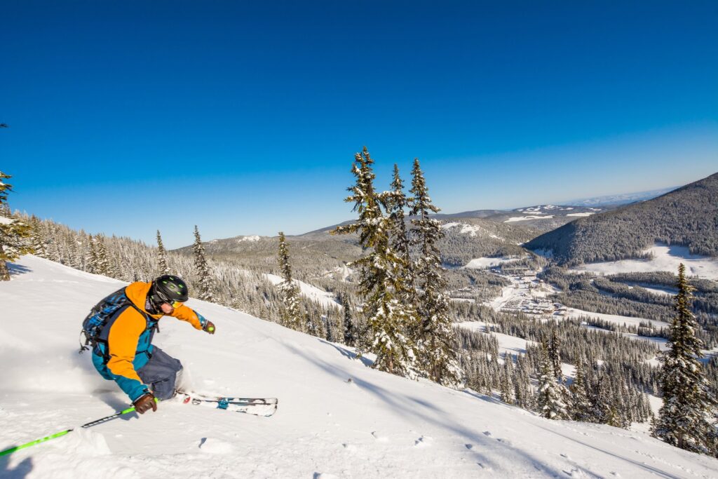 apex mountain resort skiier going downhill on a bluebird day