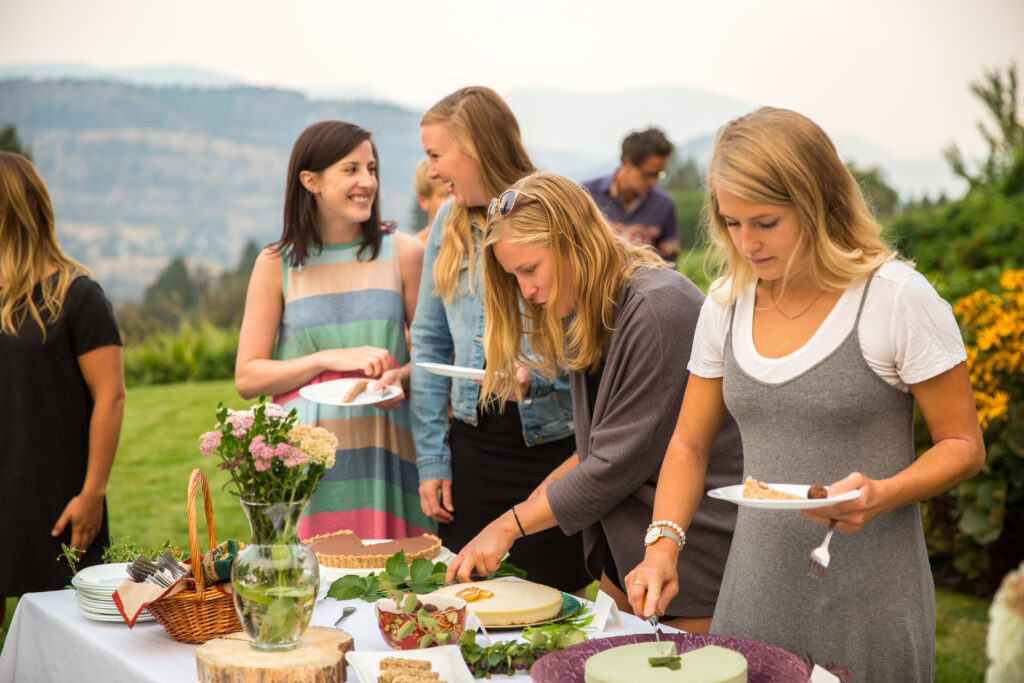 4 women enjoying Gratify treats at an outdoor event overlooking okanagan lake