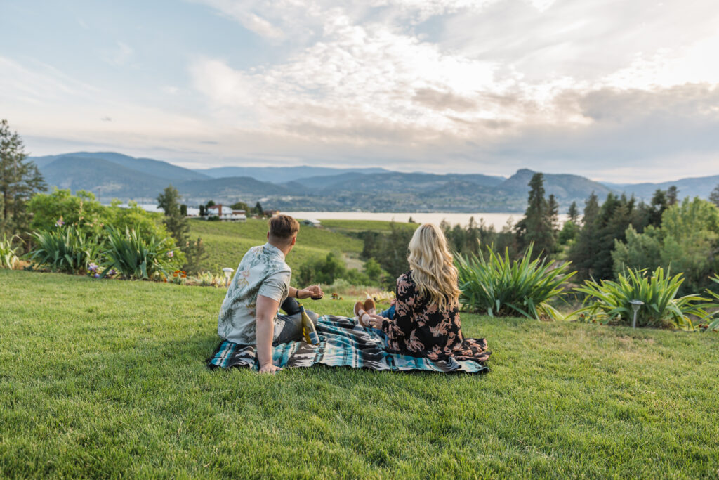 man and women enjoying a picnic at Legend Distilling grass area overlooking okanagan lake