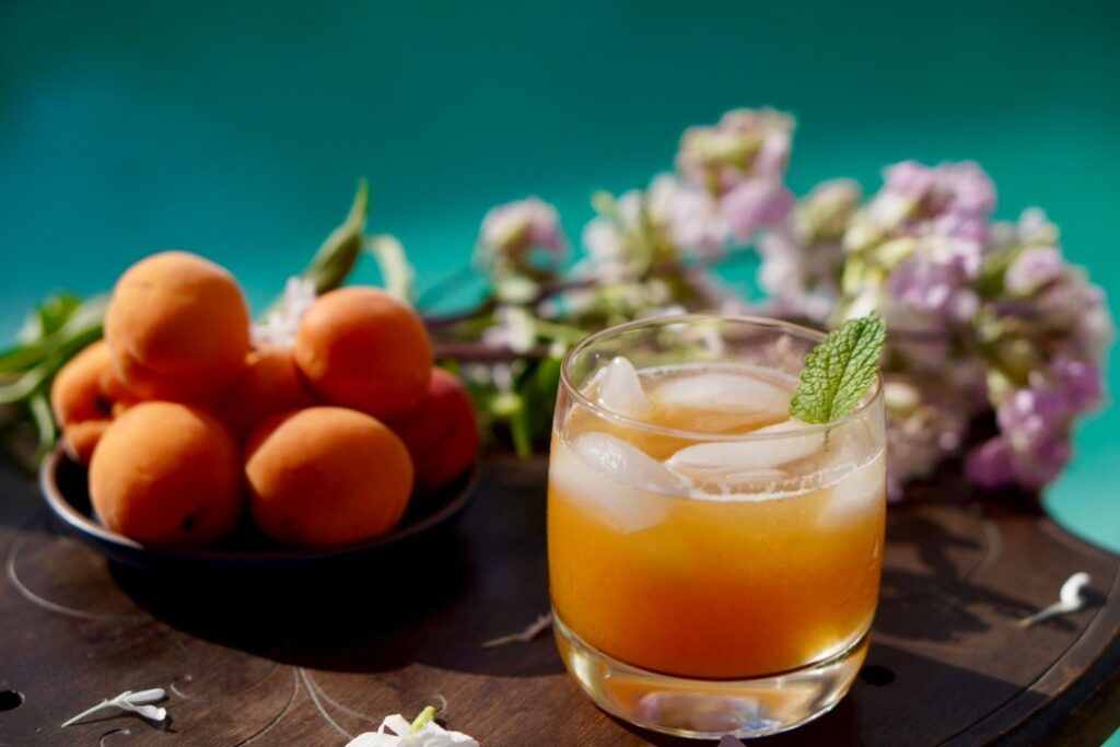 a bowl of apricots and cocktail glass on a table