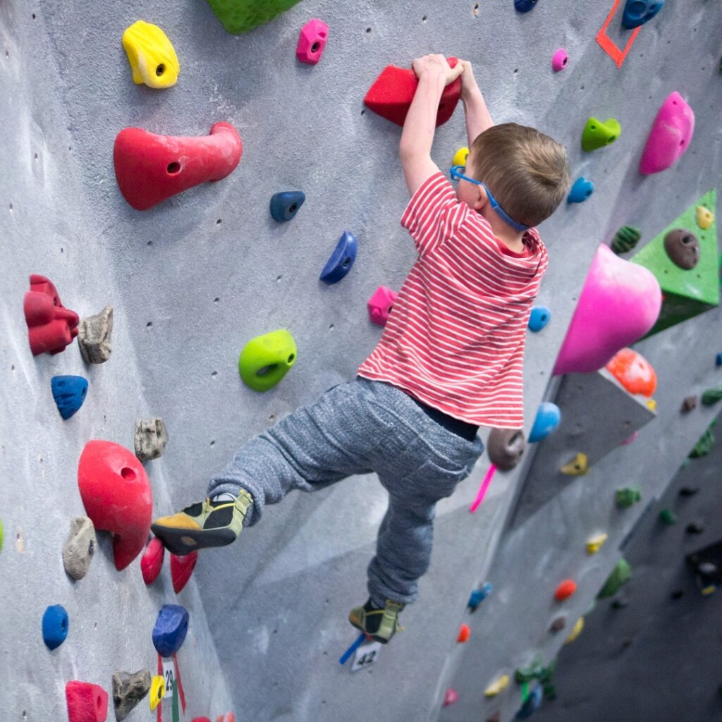 Young boy climbing the indoor climbing wall at Hoodoo Adventures