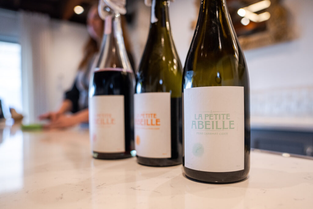 three bottle of cider in a row on the tasting room counter from La Petite Abeille Cidery in Naramata