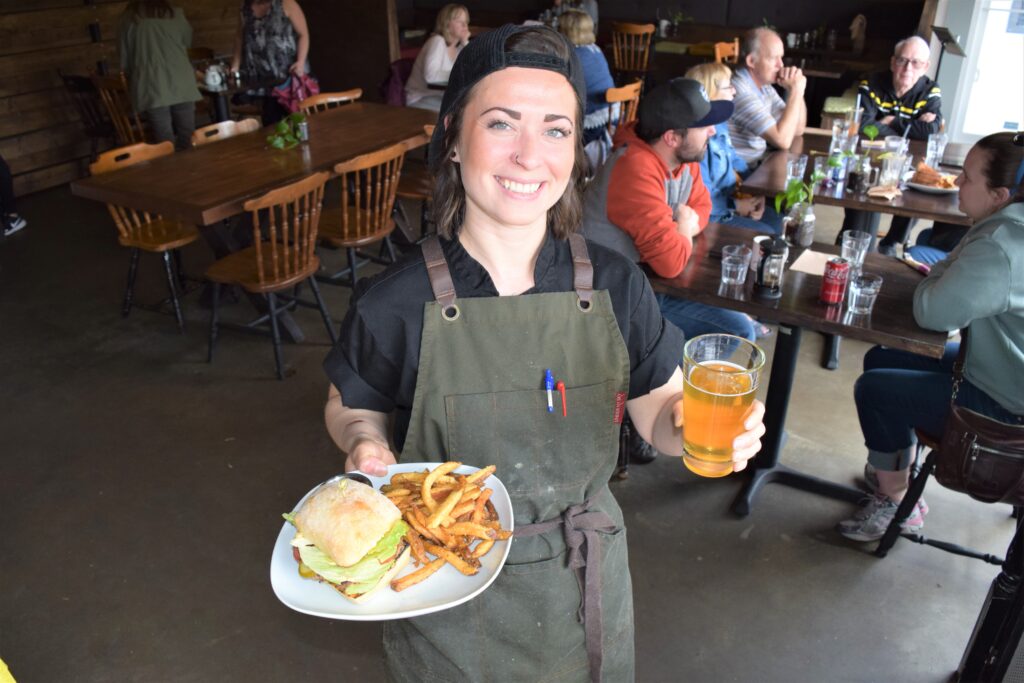 The chef at Loki's Garage is pictured holding beer and burger with fries.