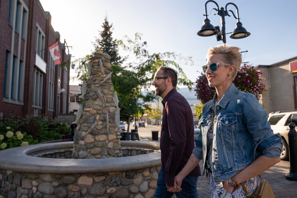 Downtown Penticton, a couple walking near petrasek, in front of an outdoor fountain