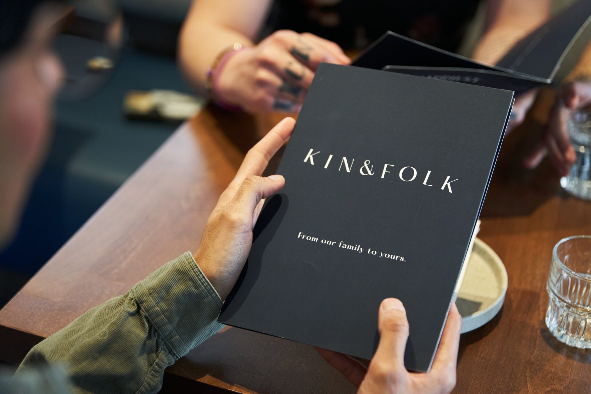 Kin & Folk Restaurant menu in diner's hands