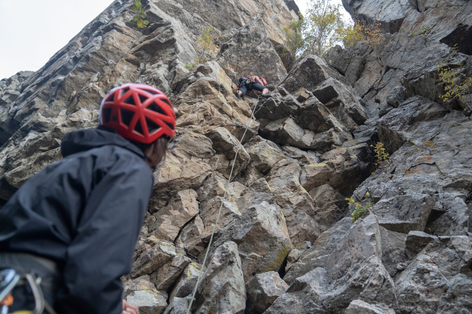 skaha bluffs climbing - belayer looking up at rock and climber