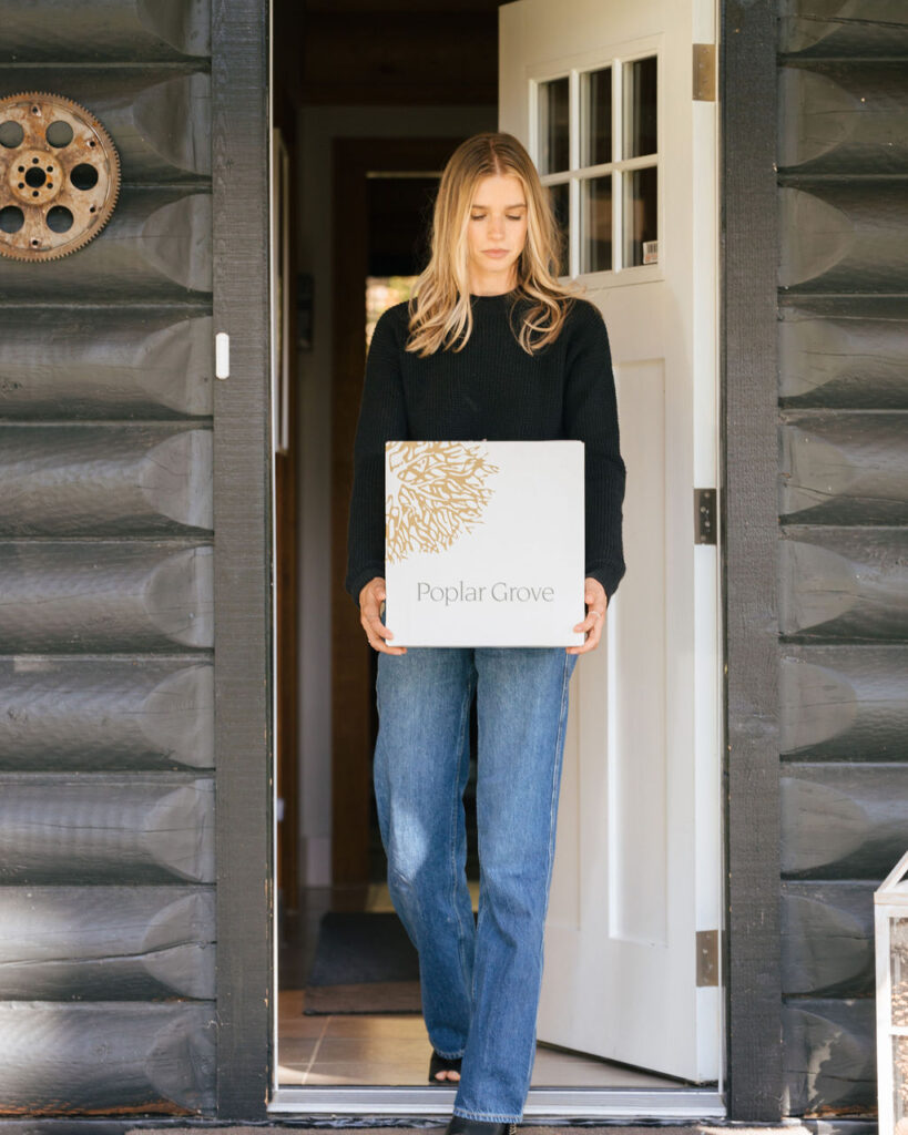 A girl walking out of a house with a Poplar Grove Wine box.