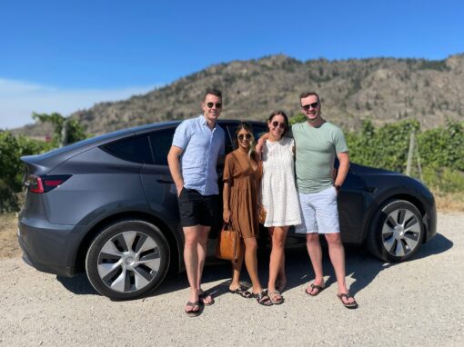 4 guests stand in front of a Tesla Model Y on their private eco-luxury wine tour in the Okanagan | Farm to Glass Wine Tours
