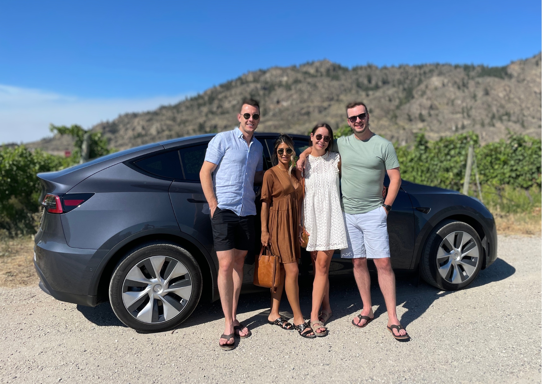 4 guests stand in front of a Tesla Model Y on their private eco-luxury wine tour in the Okanagan | Farm to Glass Wine Tours